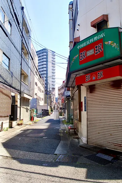 緑と赤の看板の中国庶民料理の店と、奥へ続く細い道