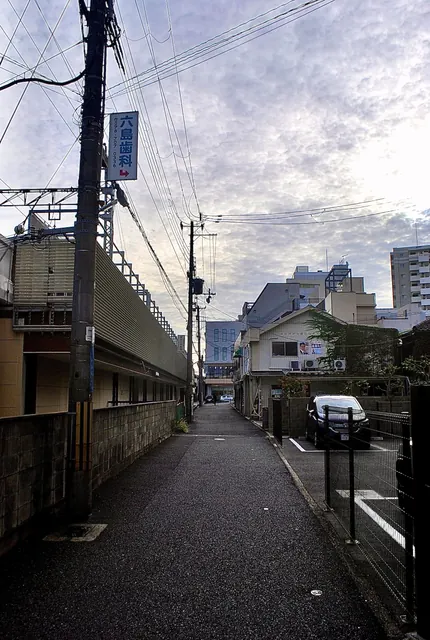線路の高架に沿って続く道と、雲の広がる空