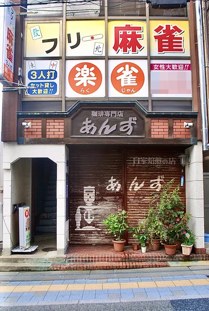 大きな麻雀店の看板の下に、喫茶店の店先が並ぶ建物