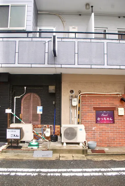 茶色いアーチの扉と、小さな飲み処の看板がある店先