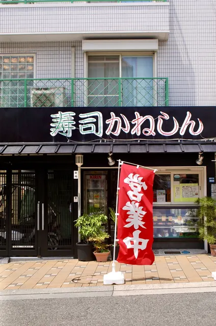 黒い店構えに赤い「営業中」ののぼりが立つ寿司屋