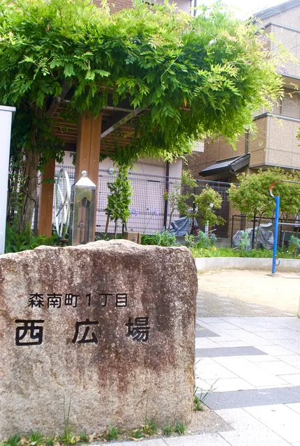 「森南町1丁目 西広場」と刻まれた石と、藤棚のある広場