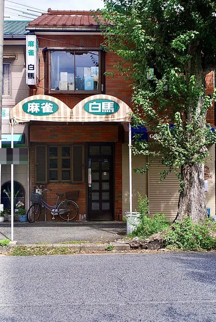 しましまのひさしに「麻雀」「白馬」の文字が並ぶ店先