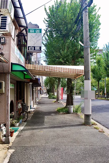 しましまの日よけと並木の下、まっすぐ続く大通りの歩道