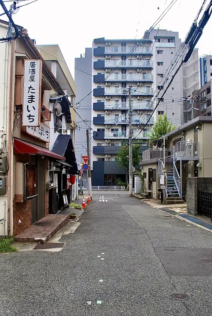 居酒屋「たまいち」の看板と、マンションの見える細い道