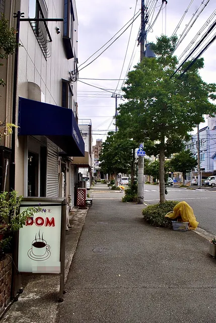 コーヒーカップの絵の「DOM」の看板と、まっすぐな歩道