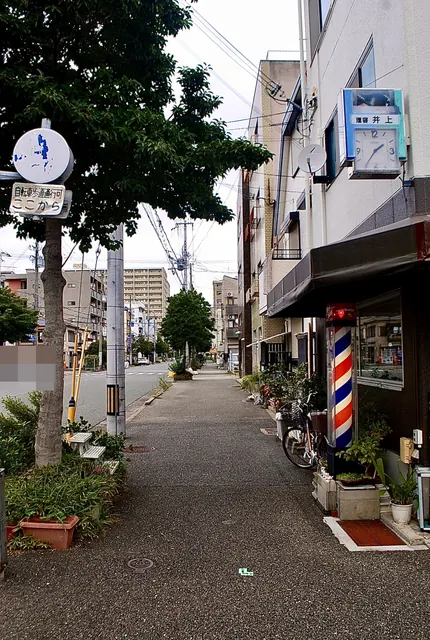 赤白青のサインポールの理容店と、並木の続く歩道