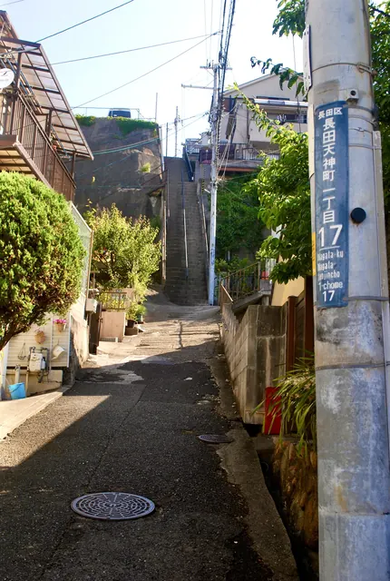 町名表示のある電柱の脇から、奥の石段へ続く路地