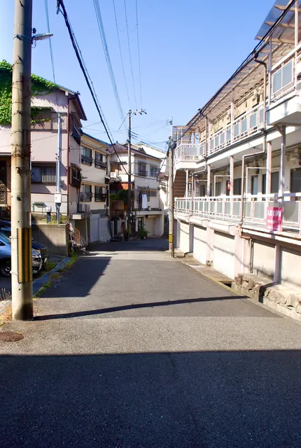 古いアパートと電柱が並ぶ、静かな住宅街の通り