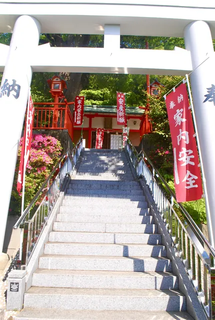 白い鳥居の先に、赤い幟の並ぶ石段の参道が続く風景