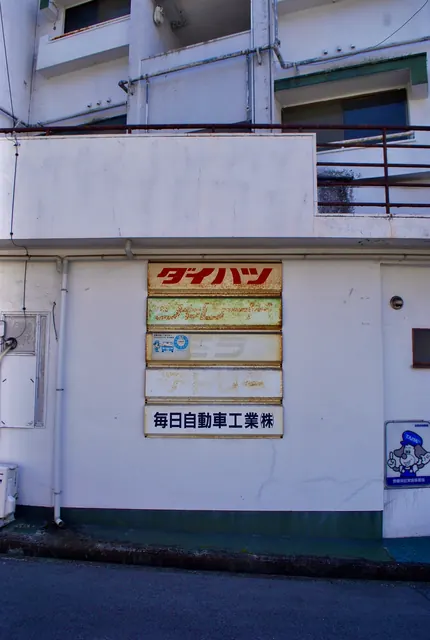 ピンクの喫茶店の看板の先に、奥へ続く坂の通り