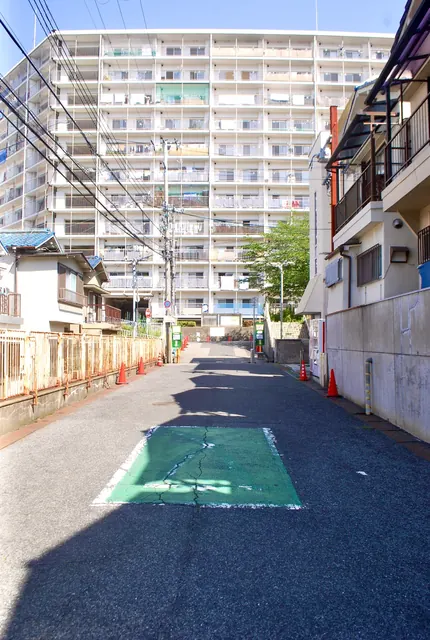 フェンス沿いのまっすぐな道の先に、大きな団地が見える風景