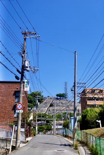 電柱の立つ線路沿いの坂の先に、鉄塔が見える風景