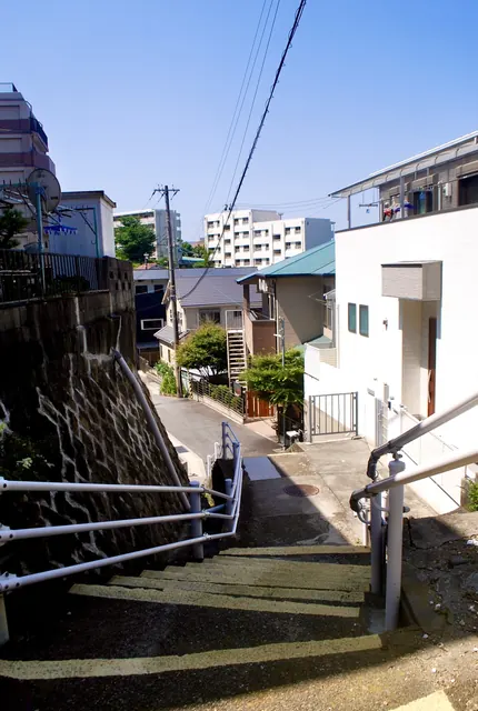 白い手すりのついた、石垣沿いを下る階段