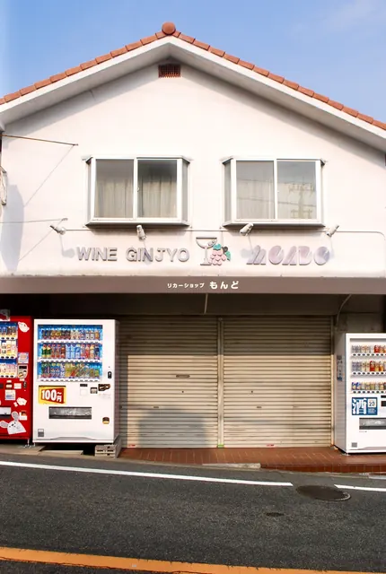「WINE GINJYO」の文字と自動販売機が並ぶ、とんがり屋根の酒店
