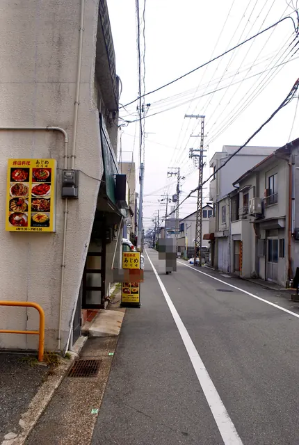 黄色い韓国料理のメニューの看板の先に、まっすぐ続く道