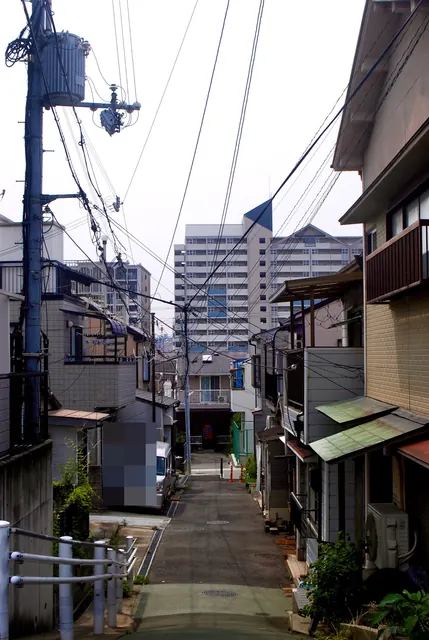 高台から、家々と車の止まる細い路地を見下ろす風景