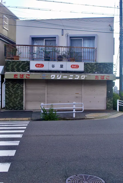 「たばこ」と「クリーニング」の看板が掛かる、シャッターの下りた古い店