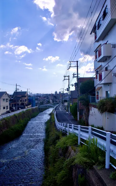 川と並んで続く道の先に、遠くの街並みが見える風景
