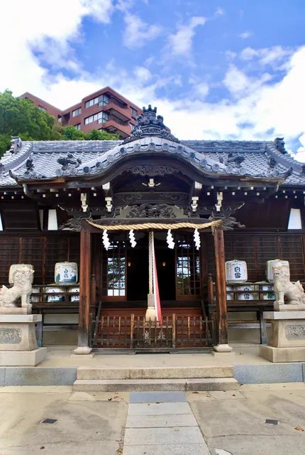 青空と雲を背に、狛犬としめ縄のある神社の拝殿