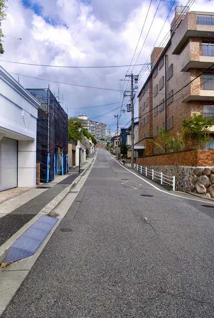 レンガ色のマンションの脇を、奥へまっすぐ上っていく坂道