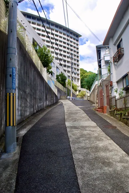 高い壁と大きな集合住宅のあいだを上っていく坂道