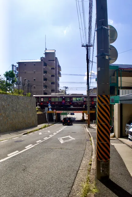 電柱の立つ道の先で、ガード下の線路を電車が渡っている風景