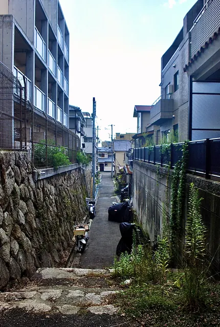 苔むした石垣に沿って、バイクの並ぶ細い路地
