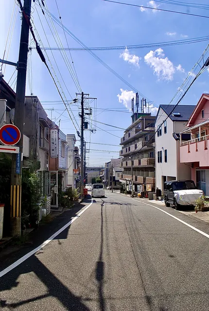 電柱と電線が奥へ続く、青空の下の通り