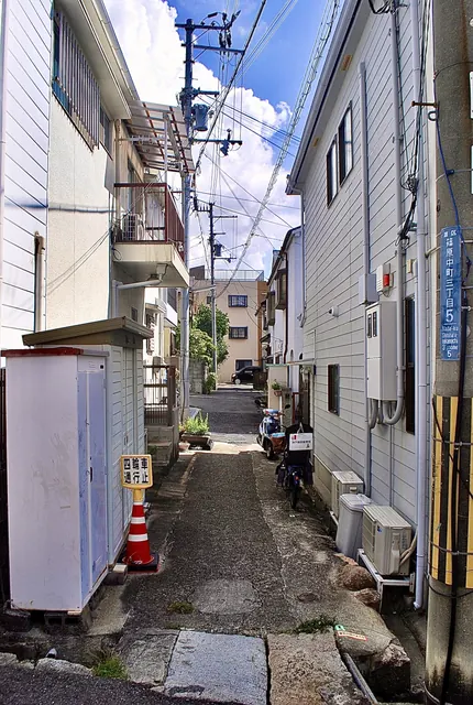 町名表示のある電柱と、家々のあいだを奥へ続く細い路地