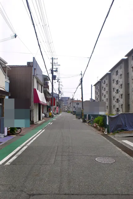 赤いひさしの店と団地のあいだを、まっすぐ続く通り
