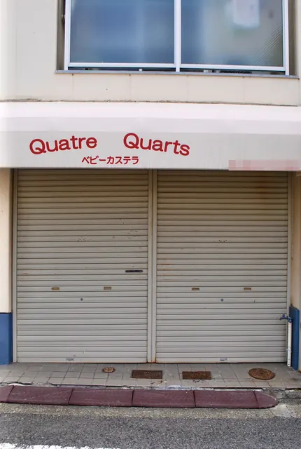 赤い文字の「Quatre Quarts」とシャッターの、ベビーカステラの店
