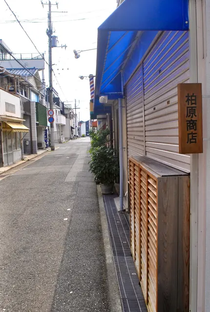 木の看板と木の箱が並ぶ、シャッターの店の前の通り