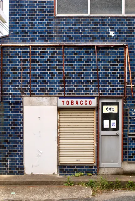 青いタイルの壁と「TOBACCO」の看板が残る、古いたばこ屋
