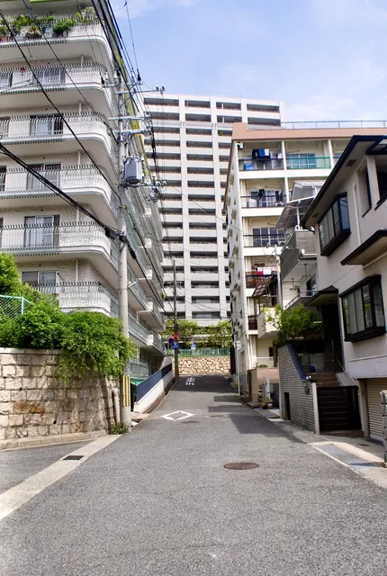 高いマンションに挟まれ、奥へ上っていく坂道