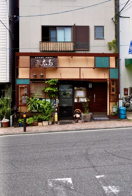 格子と植木鉢に囲まれた、民芸調の居酒屋の店先