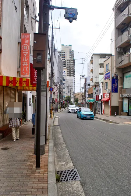 縞模様の日よけの店の前から、商店街の通りを見通す風景