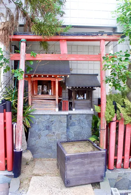 建物のあいだにたたずむ、赤い鳥居の小さなお社