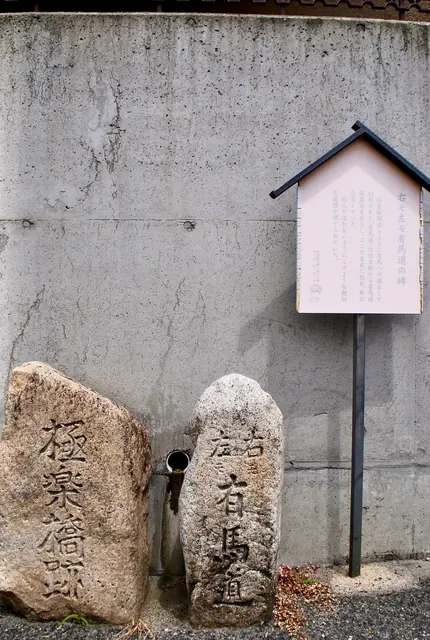 「有馬道」と刻まれた古い石の道しるべと、案内の看板