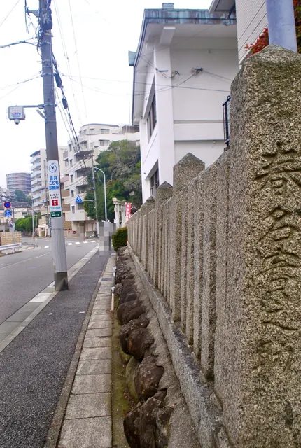石の玉垣が続く歩道の先に、神社の鳥居と幟が見える通り