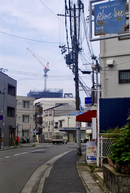 美容室の看板と電柱、電線が入り組む駅前の通り