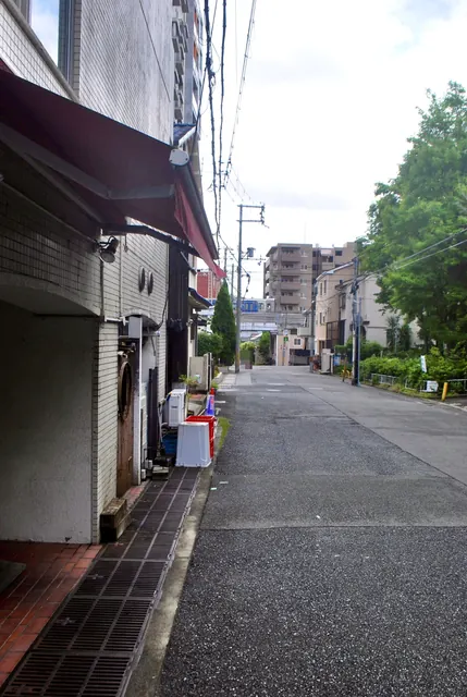 白いタイル張りの店先に沿って、奥の緑へ続く細い道