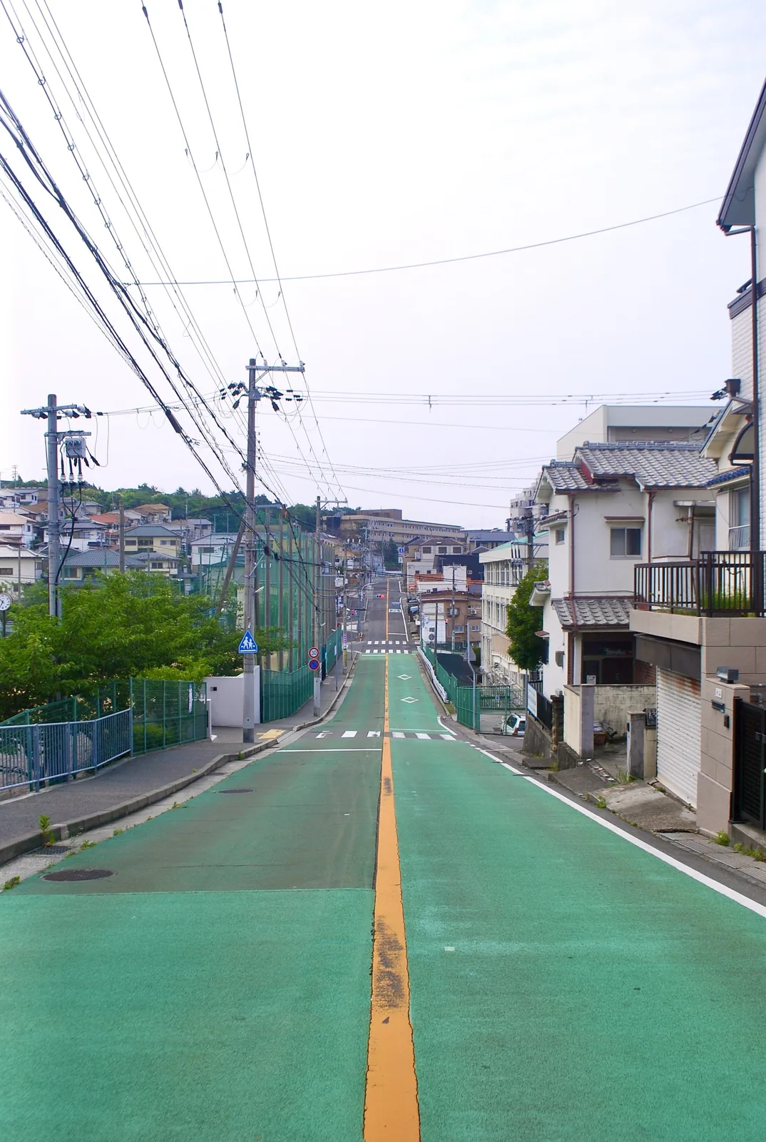 緑に塗られた路面の坂道が、遠くの街並みまでまっすぐ伸びる風景