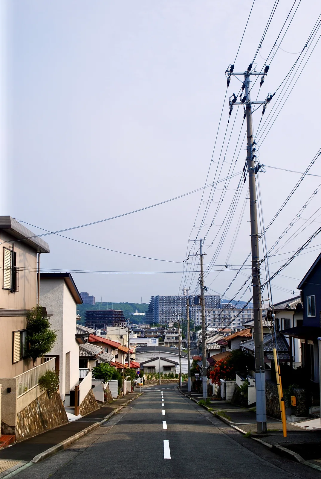電柱と家々のあいだを、遠くの団地へまっすぐ下る坂道