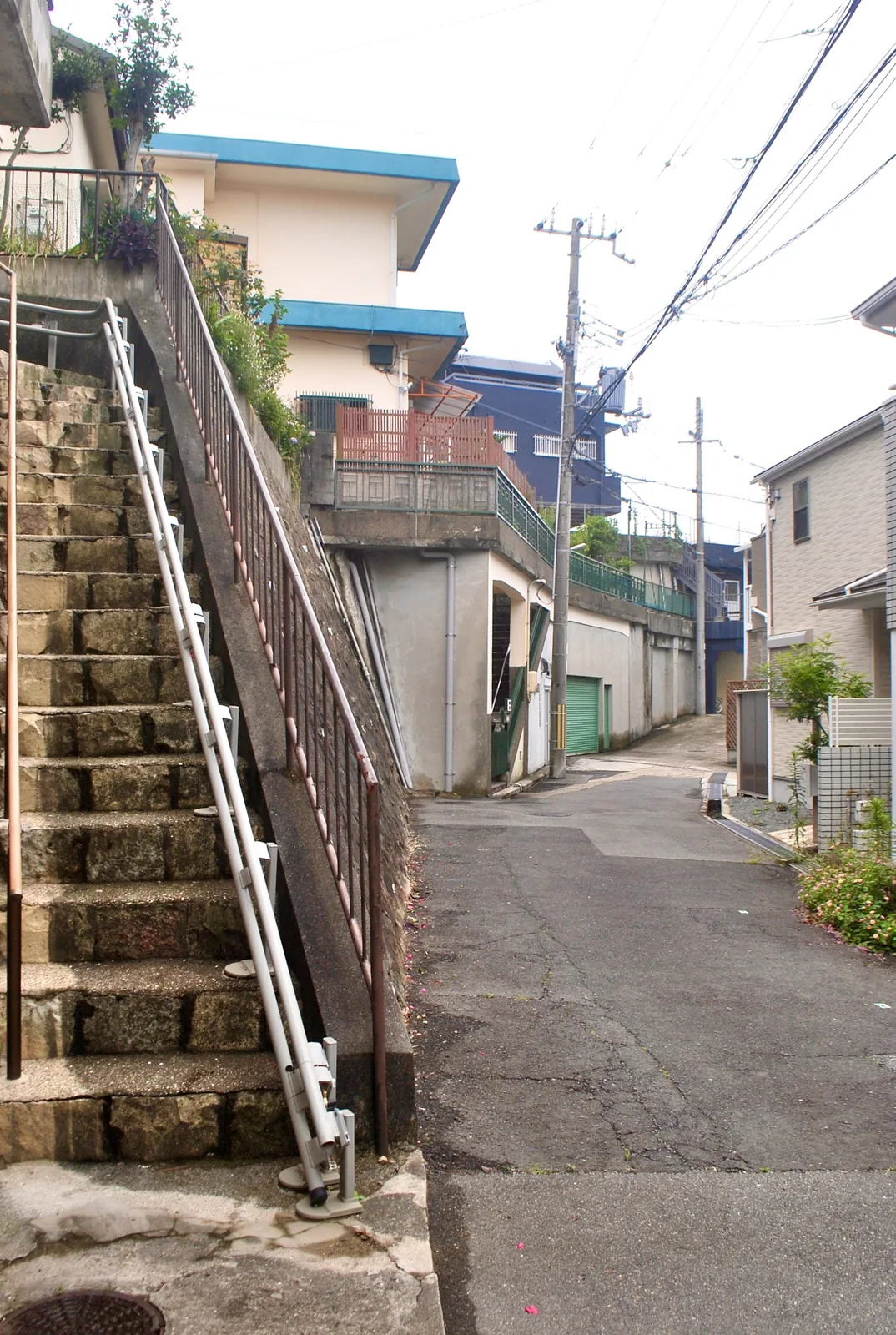 手すりのついた石の階段が、家の脇を上へ続く風景