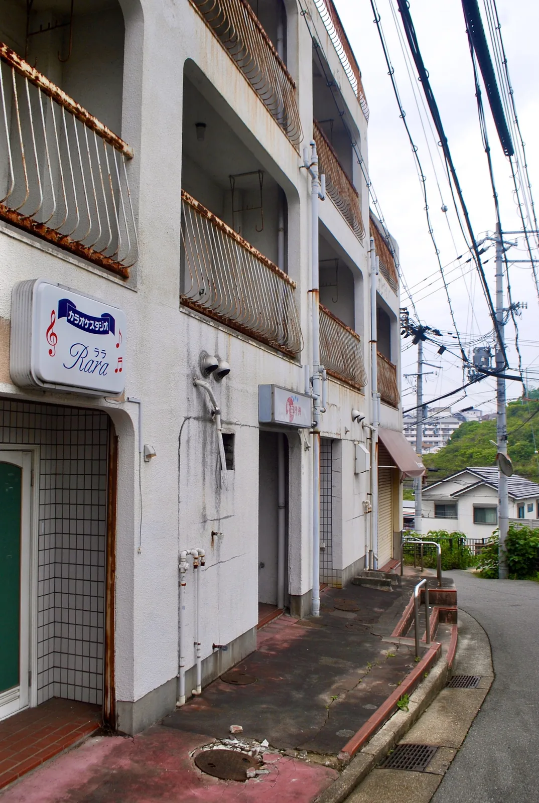 「カラオケスタジオ Rara」の看板と、タイル張りの入口