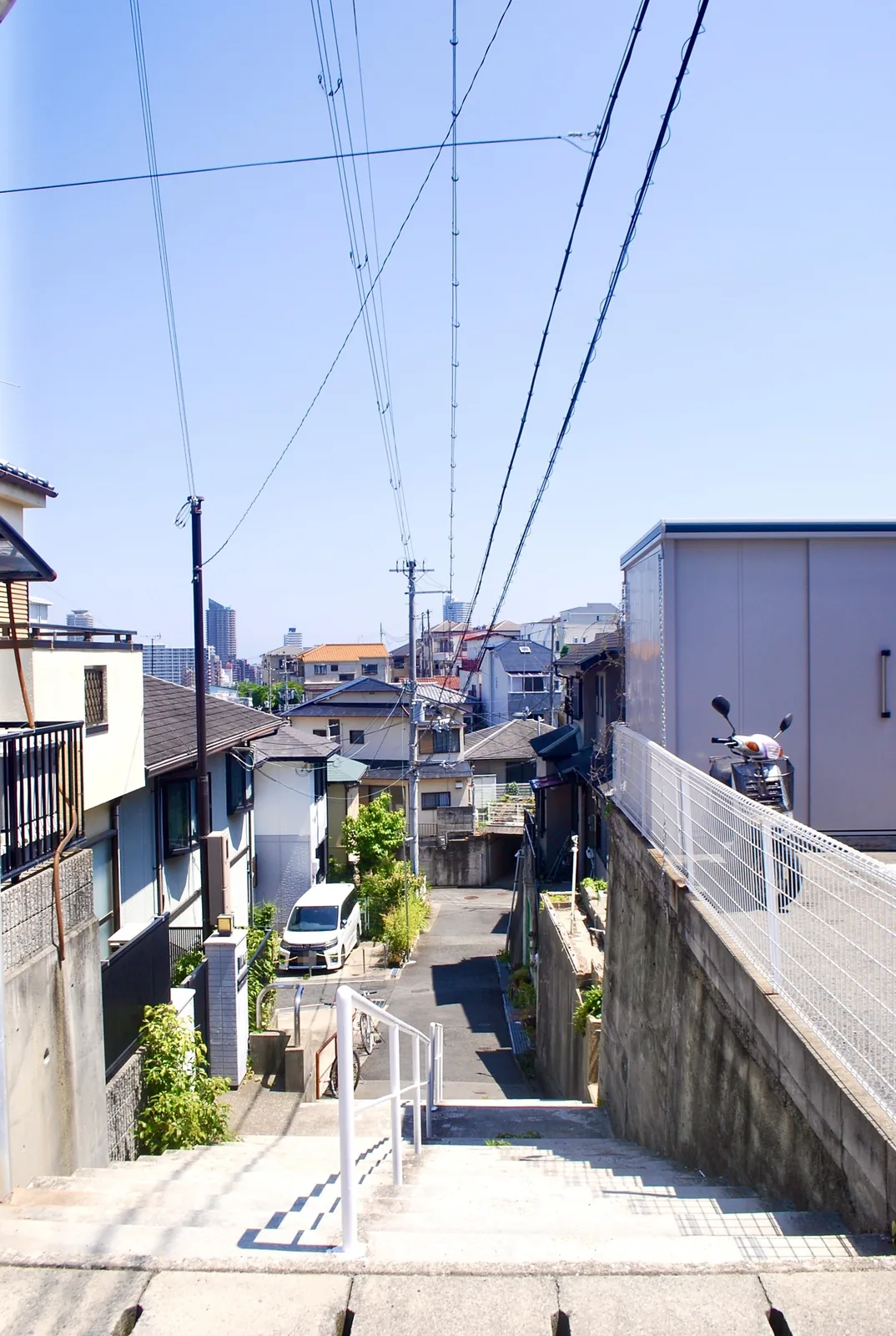階段の上から、家々のあいだを抜ける道と町並みを見下ろす風景