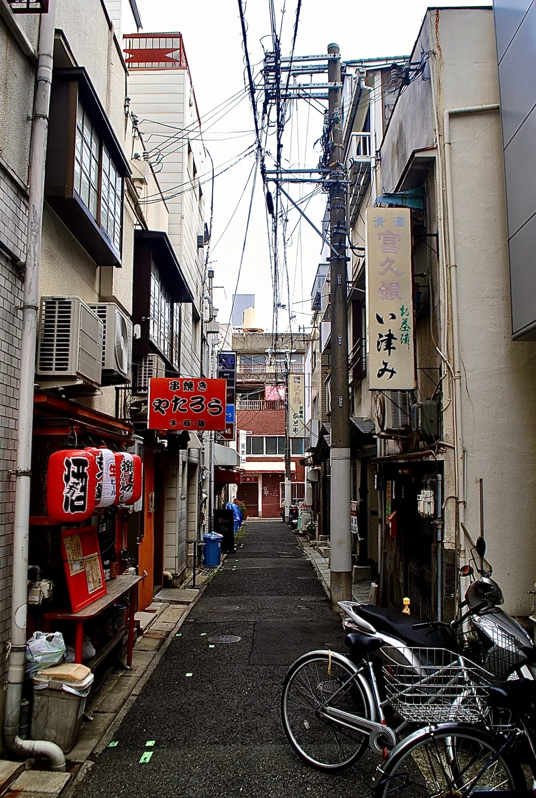赤い提灯と「串焼き やたろう」の看板が並ぶ、細い路地