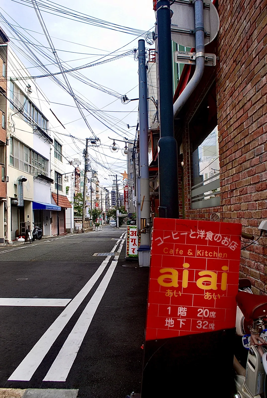 「aiai」の赤い看板と、白い二重線の続く道