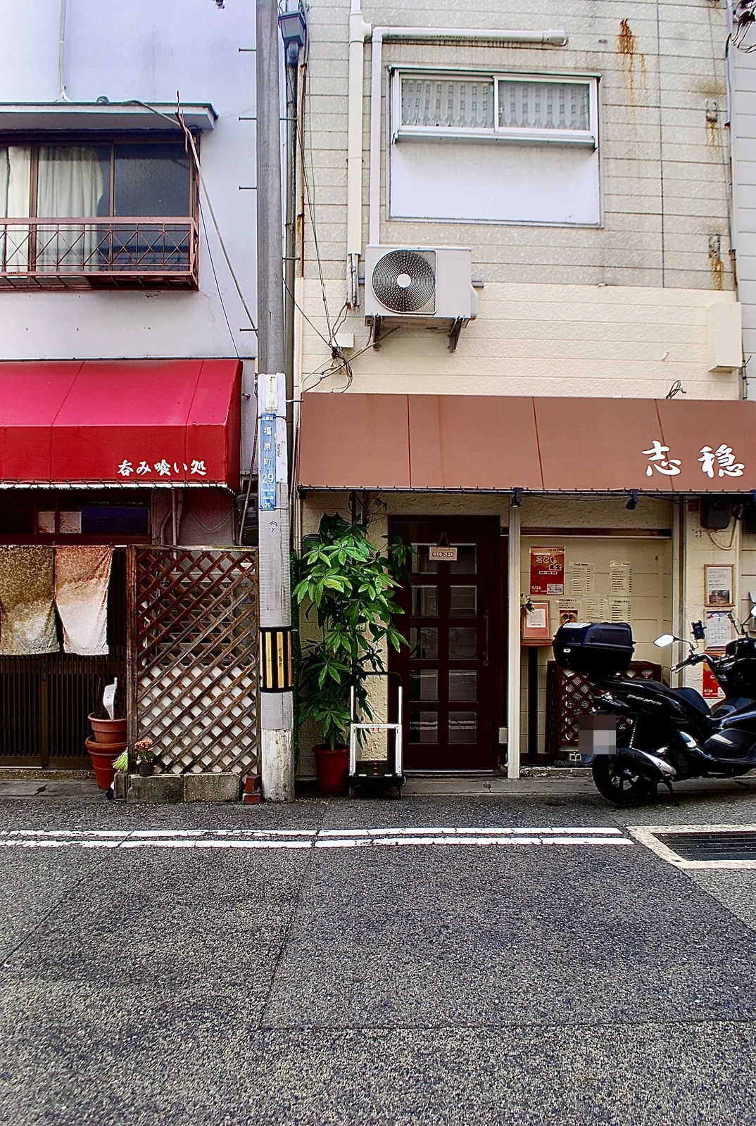 赤い日よけの「呑み喰い処」と、茶色い日よけの店が並ぶ通り